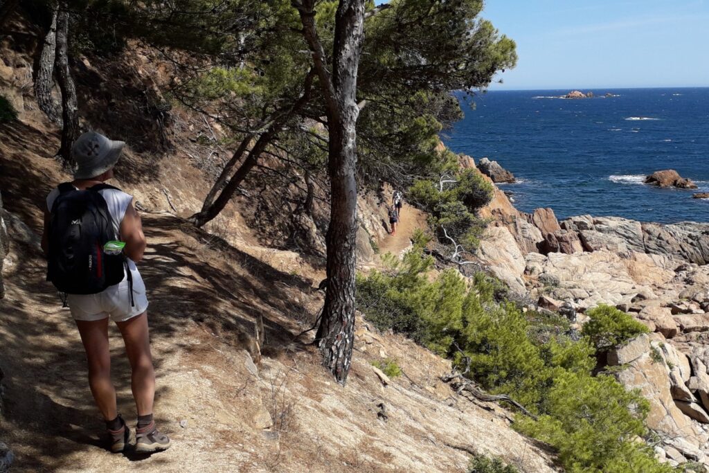 Groupe de randonneurs en Costa Brava sur un sentier côtier à l'ombre des arbres