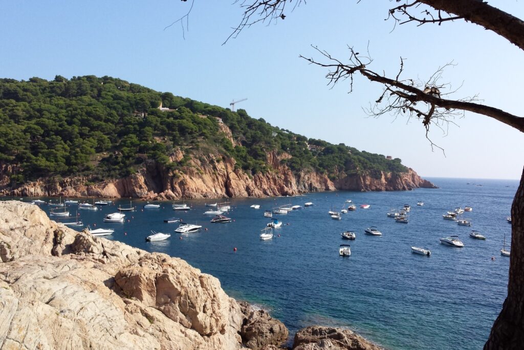 Paysage maritime avec des reliefs typiques de la Costa Brava, et des bateaux amarrés en mer