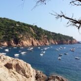 Paysage maritime avec des reliefs typiques de la Costa Brava, et des bateaux amarrés en mer