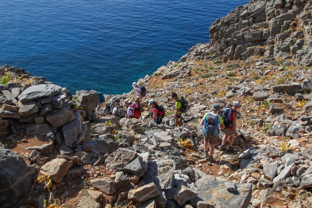 Groupe de randonneurs sur un sentier qui descend vers l'eau en Crète