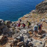 Groupe de randonneurs sur un sentier qui descend vers l'eau en Crète