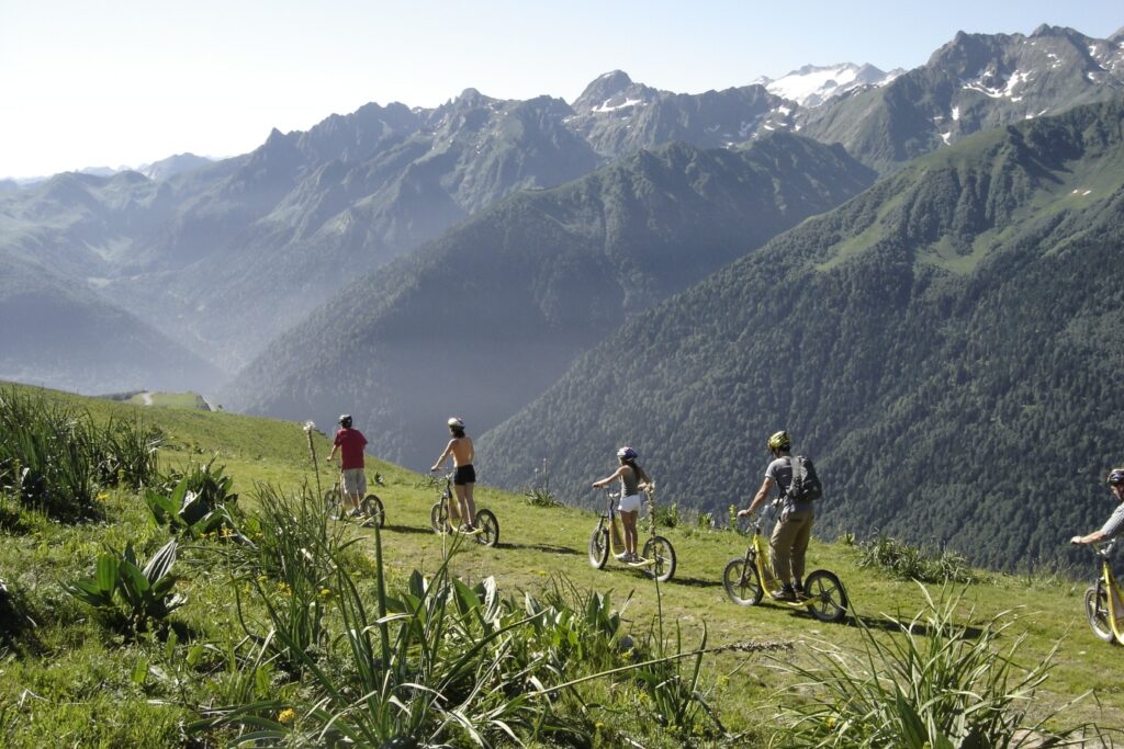 Paysage montagnard avec une famille accompagnée d'un guide en train de faire une activité en trottinette en montagne