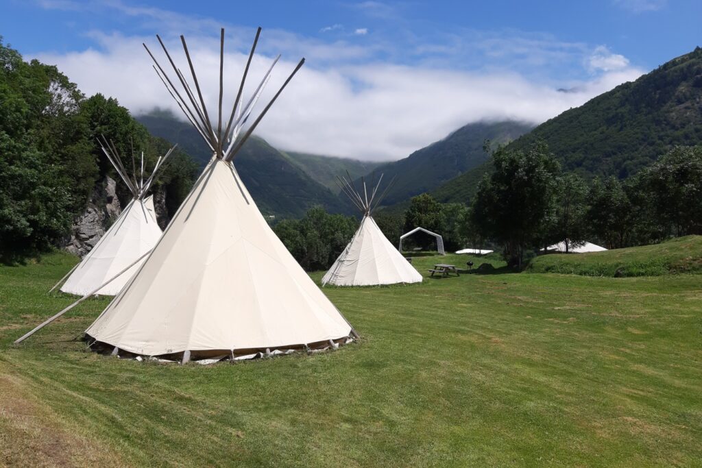 Paysage de montagne avec un champ contenant des tipis, disponible lors de séjour famille accompagné.