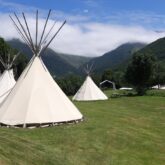 Paysage de montagne avec un champ contenant des tipis, disponible lors de séjour famille accompagné.