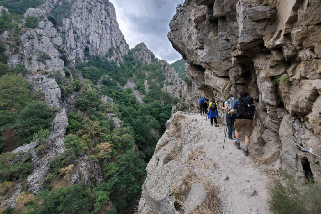 Paysage de montagne avec un sentier de randonnée sur la droite de l'image, le sentier est ancré dans la roche