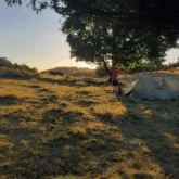 Prise de vue au coucher du soleil d'un camp en tente lors d'un séjour familial avec des randonnées et des ânes dans les Pyrénées.