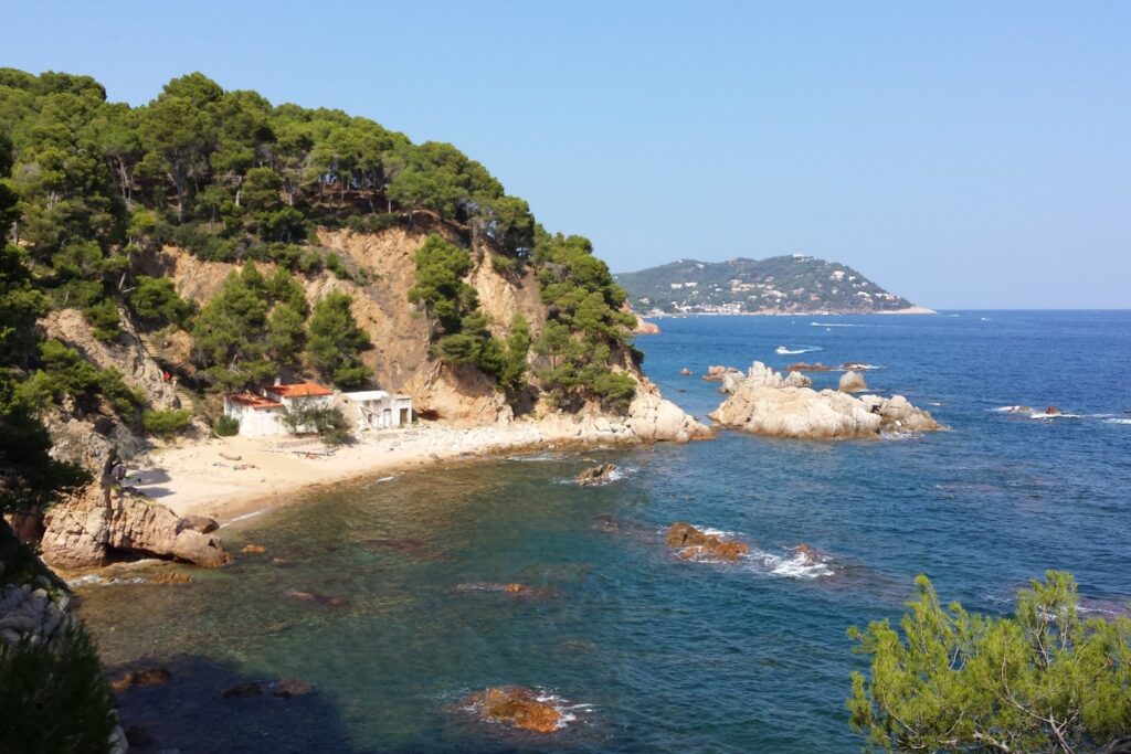 Paysage côtier estival avec la mer en contrebas, entouré de différents reliefs montagneux