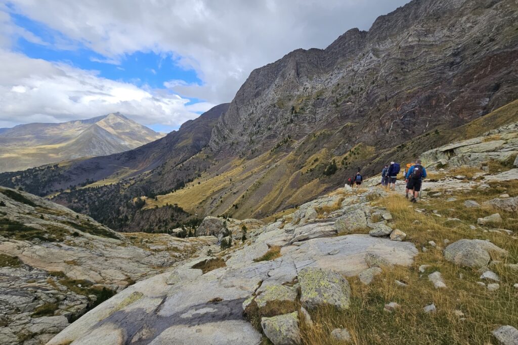 Randonneurs sur un sentier descendant une montagne et poursuivant leur randonnée du tour des Posets avec leur guide