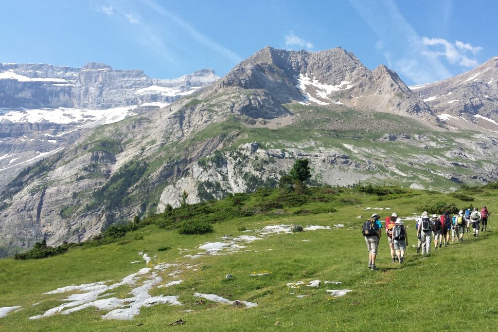 Groupe de randonneurs sur un sentier avec leur guide, paysage montagnard avec des sommets encore enneigés