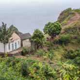 Paysage mêlant la mer et la montagne au Cap-Vert avec une maison en bord de mer et des arbres, au Cap-Vert