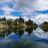 Lac de montagne avec reflets des reliefs dans l'eau dans les Encantats.