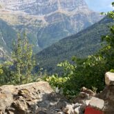 Paysage avec en fond les sommets dans la zone de Ordesa et au premier plan des roches, notamment une balisée signalant le chemin