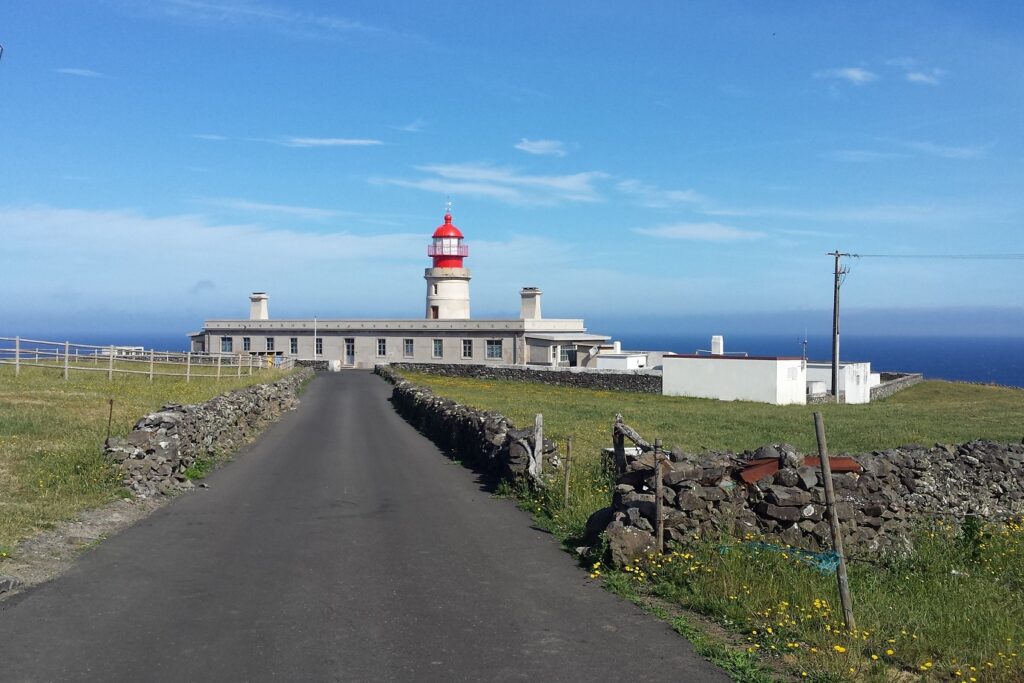 Paysage des Açores en bord de mer avec une route et au bout de la route un phare