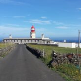 Paysage des Açores en bord de mer avec une route et au bout de la route un phare
