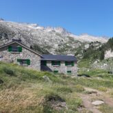 Paysage de montagne avec des sommets en arrière-plan et une maison en pierre au premier plan dans la montagne