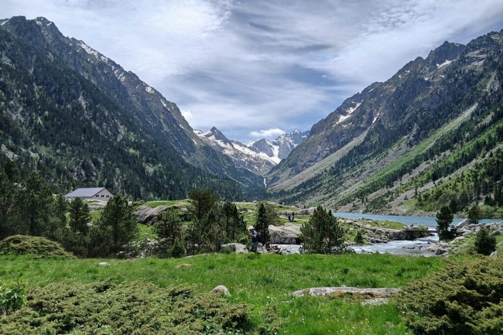 Paysage montagnard avec des sommets en fond et au premier plan un plateau avec des arbre et un cours d'eau