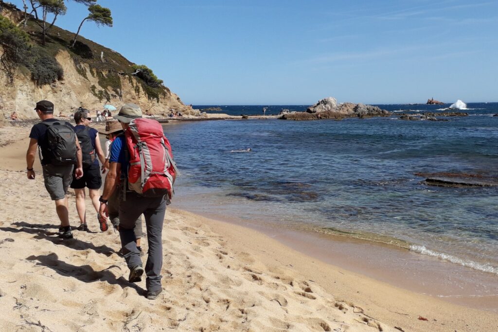 Groupe de randonneurs en train de marcher sur la plage en Cosat Brava sans guide lors d'un séjour en semi- itinérance.
