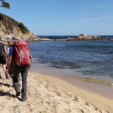 Groupe de randonneurs en train de marcher sur la plage en Cosat Brava sans guide lors d'un séjour en semi- itinérance.