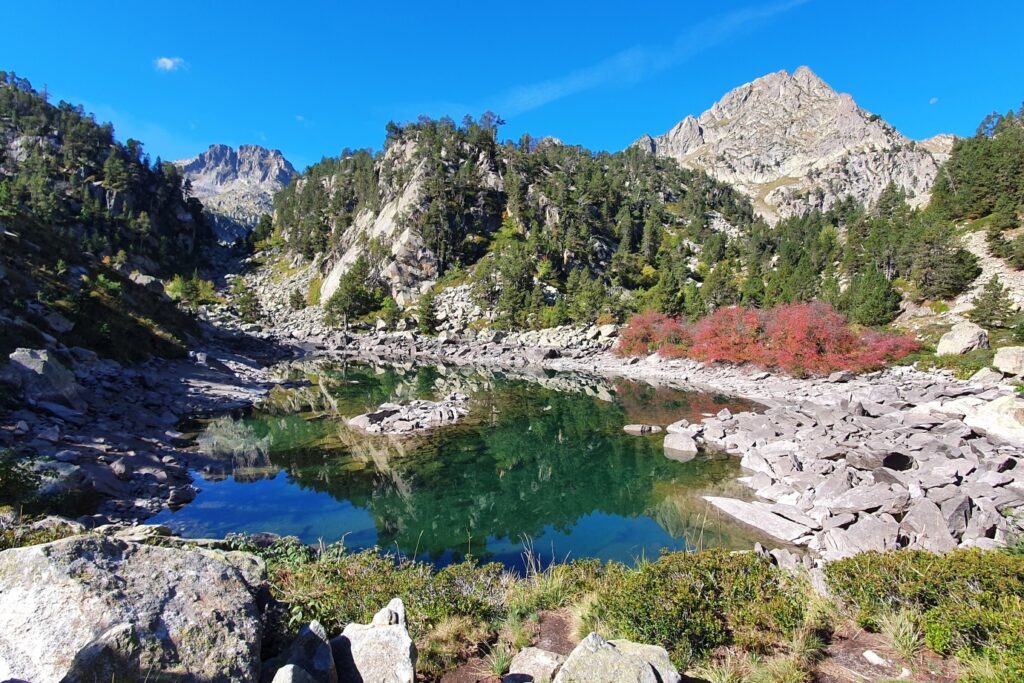 Paysage de montagne avec des sommets et un petit lac au pied de reliefs avec de la végétation diverse