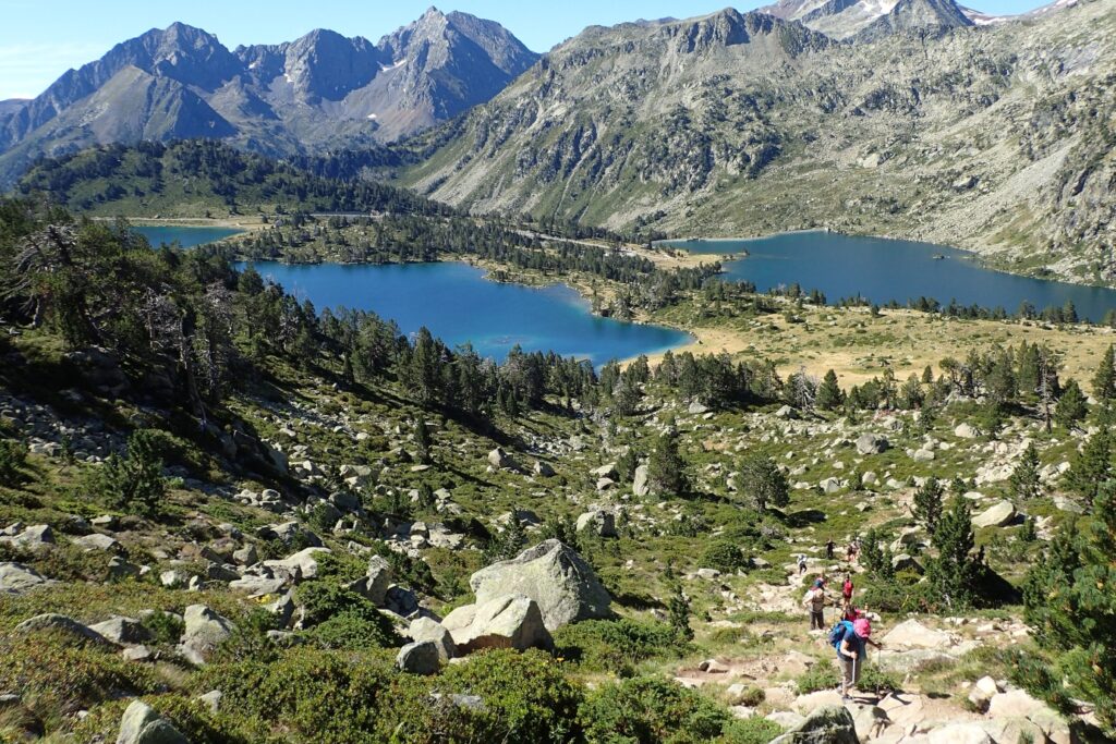 Paysage montagnard avec des lacs en contrebas, entouré de verdure, avec des sommets à l'arrière-plan