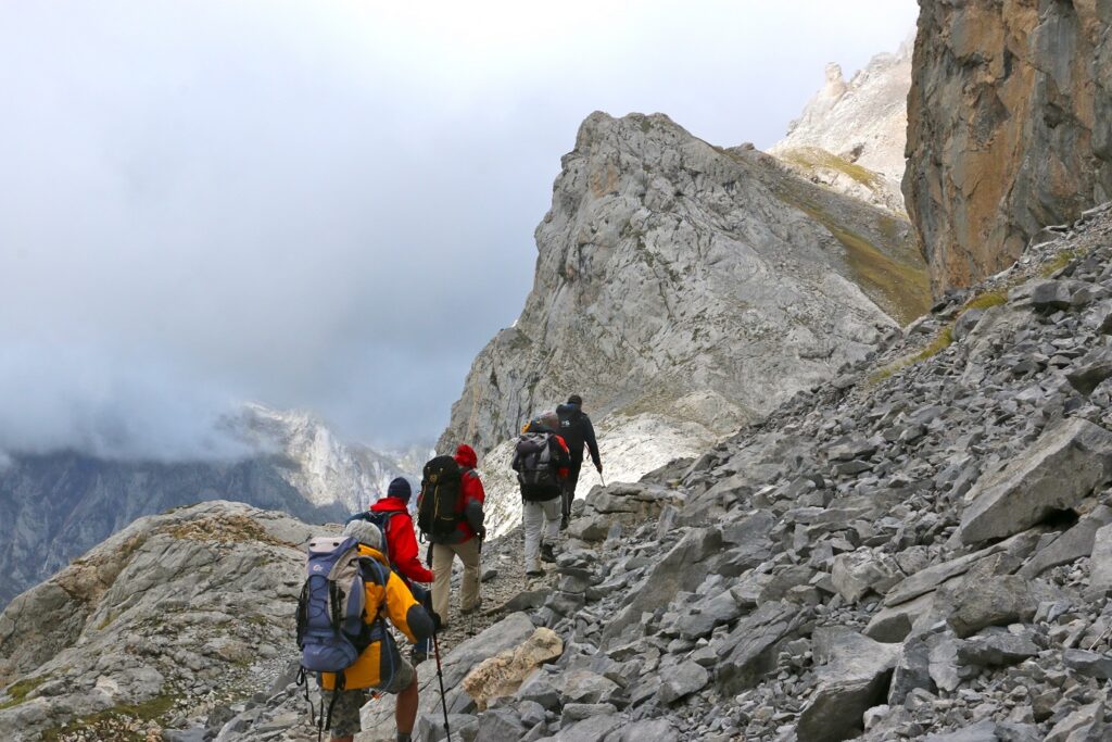 Groupe de randonneurs avec leur guide qui avancent sur un sentier de pierre dans les Picos de Europa
