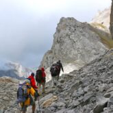 Groupe de randonneurs avec leur guide qui avancent sur un sentier de pierre dans les Picos de Europa