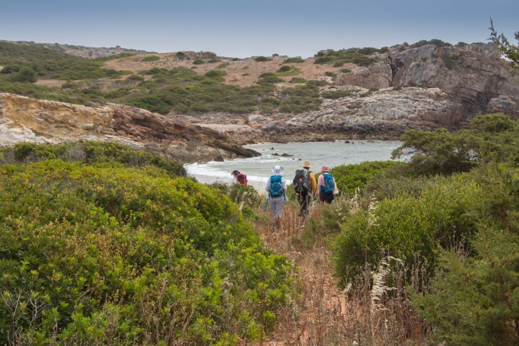 Groupe de randonnée sur un sentier se dirigeant vers une étendue d'eau au Portugal