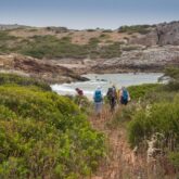 Groupe de randonnée sur un sentier se dirigeant vers une étendue d'eau au Portugal