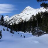 Paysage hivernal dans les Pyrénées proche de l'Aneto, avec en fond un sommet à la lumière du soleil couvert de neige.