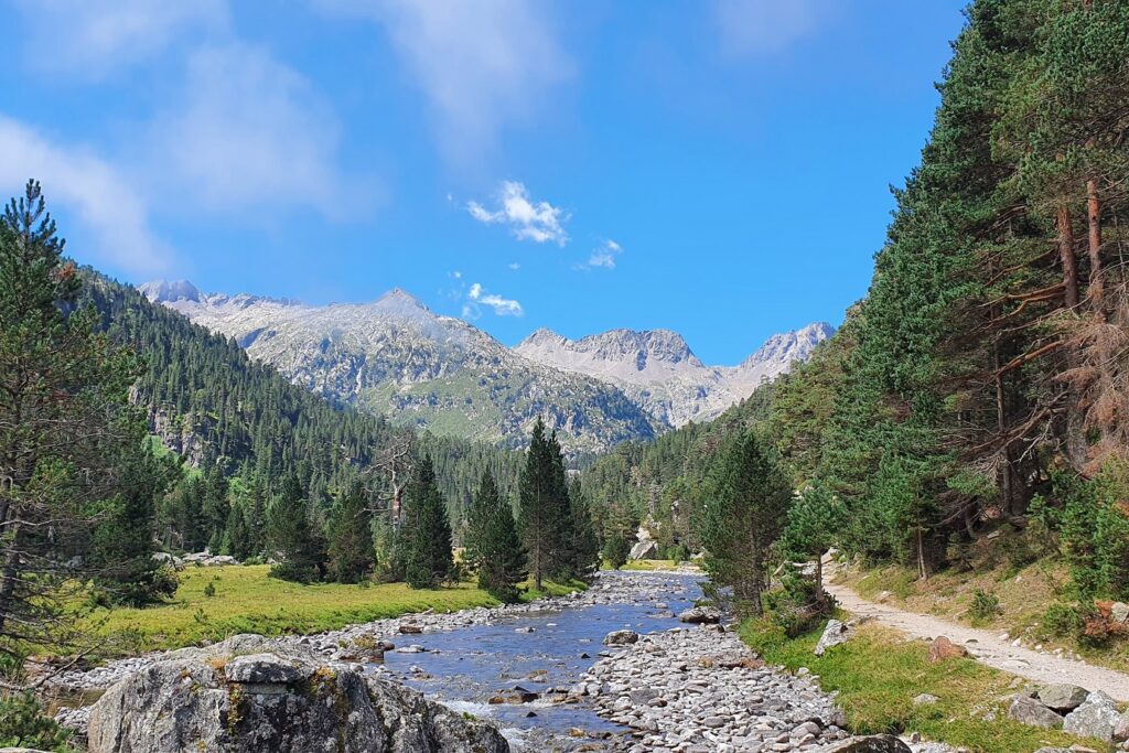 Paysage montagnard avec un cours d'eau en milieu d'image, avec des sentiers en bord de cours d'eau