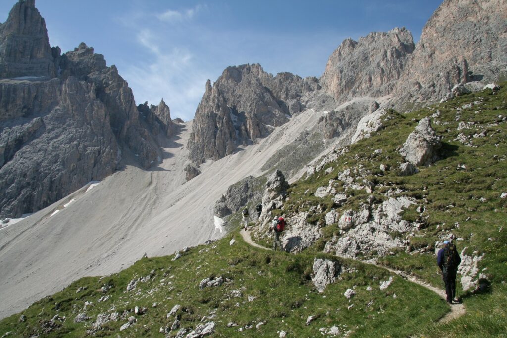 Paysage dans le massif des Dolomies avec un sentier à flanc de montagne, et des sommets aux couleurs grises en contrebas