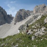 Paysage dans le massif des Dolomies avec un sentier à flanc de montagne, et des sommets aux couleurs grises en contrebas