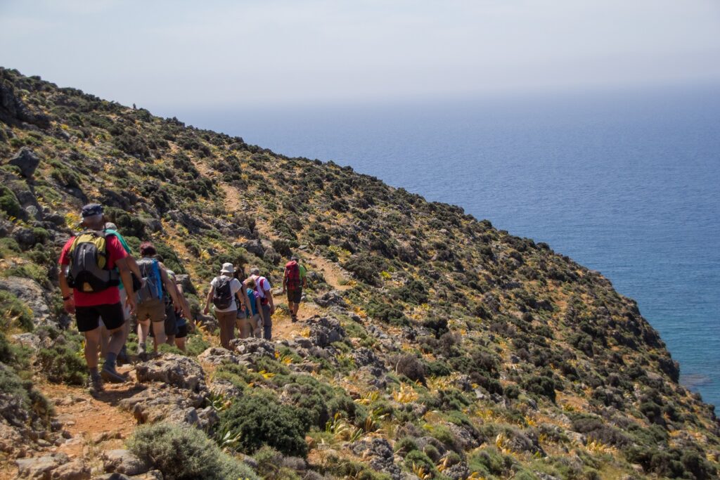 Groupe de randonneurs sur un entier en train de descendre une montagne avec la mer en contrebas
