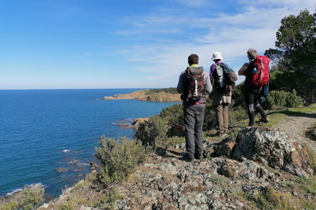 Groupe de randonneurs face à la vue de la mer sur leur chemin de randonnée