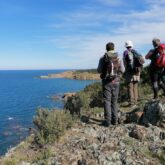 Groupe de randonneurs face à la vue de la mer sur leur chemin de randonnée