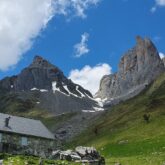 paysage de montagne avec le pied enneigé, paysage avec des sommets en fond et une maison en pierre au premier plan