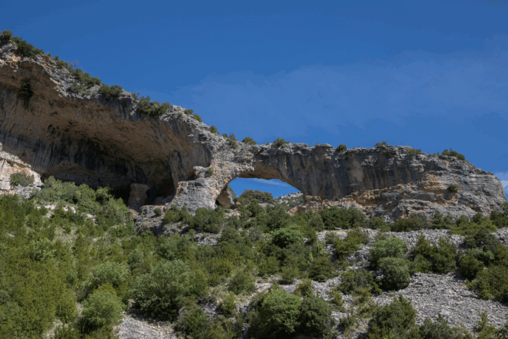 Paysage Sierra de Guara avec roche typique en contre-haut avec un trou au sein de la roche, et en contrebas de la verdure