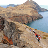 Paysage de Madère avec groupe de randonneurs sur un sentier de montagne au-dessus de l'océan.