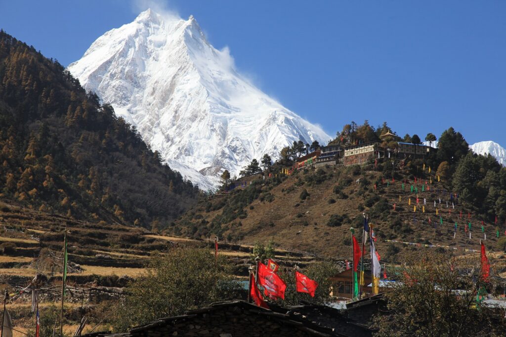 Groupe de randonneurs avec leur guide suivis par leurs porteurs sur un sentier lors du tour du Manaslu