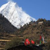 Groupe de randonneurs avec leur guide suivis par leurs porteurs sur un sentier lors du tour du Manaslu
