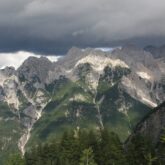 Paysage montagnard avec les flanc de montagnes recouverts de végétation et en contrebas on voit une forêt, ce paysage se présente en Slovénie dans les Alpes Juliennes