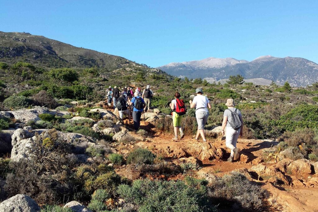 groupe de randonneurs sur un sentier en montagne en Crète avec un décor estival et de la végétation caractéristique de l'île