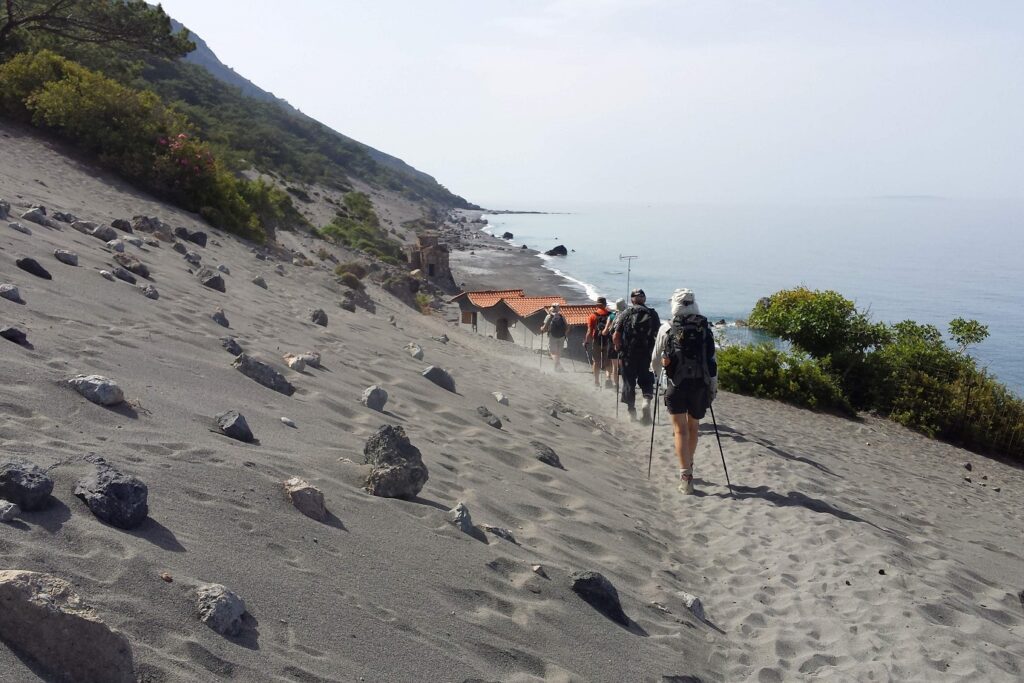 Grope de randonneurs en crète sur un sentier de sable avec la mer sur le côté