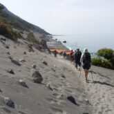 Grope de randonneurs en crète sur un sentier de sable avec la mer sur le côté