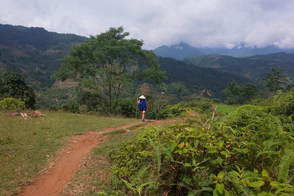 Personne sur un entier de couleur rouge encadré de végétation, avec en face des montagnes, au Vietnam