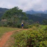 Personne sur un entier de couleur rouge encadré de végétation, avec en face des montagnes, au Vietnam