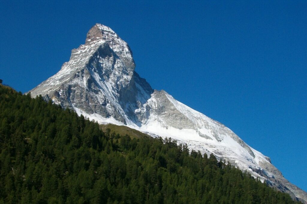 Paysage de montagne avec un sommet en fond et une forêt au premier plan observé lors de randonnées sur la haute route Chamonix-Zermatt
