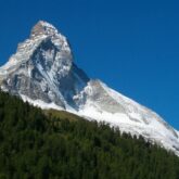 Paysage de montagne avec un sommet en fond et une forêt au premier plan observé lors de randonnées sur la haute route Chamonix-Zermatt