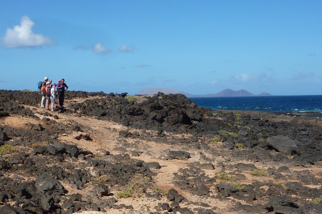 Paysage sur l'île de Lanzarote avec un groupe de marcheurs sur un sentier en bord de littoral