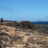 Paysage sur l'île de Lanzarote avec un groupe de marcheurs sur un sentier en bord de littoral
